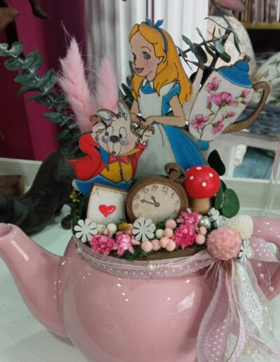 Manualidad decorativa en jarrón rosa inspirada en el tema de Alicia en el país de las maravillas.