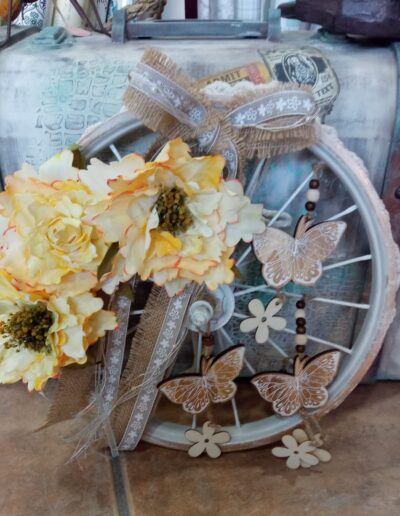Manualidad sobre rueda adornada con flores y detalles en madera